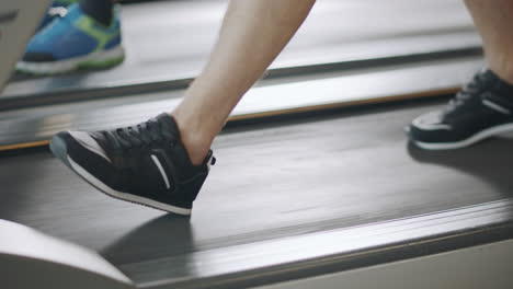 Closeup-feet-walking-on-treadmill-in-fitness-gym-slowly.