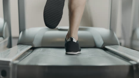 Closeup-athletic-feet-running-on-treadmill-in-fitness-gym.