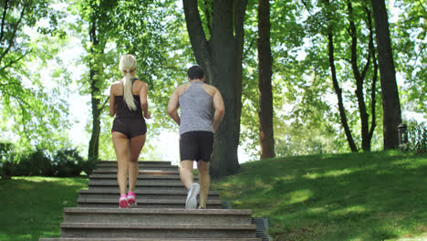 Running-couple-climbing-stairs-at-morning-run-in-summer-park