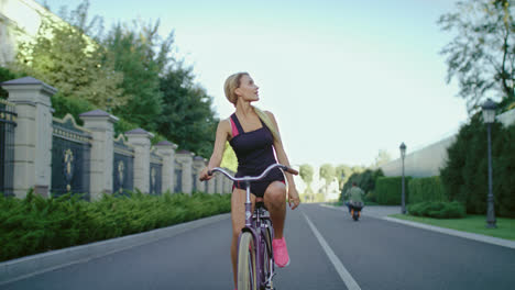 Mujer-Delgada-En-Ropa-Deportiva-Montando-En-Bicicleta-Mientras-Entrena-En-El-Parque-De-Verano
