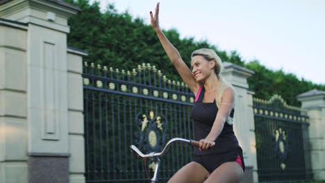 Mujer-Feliz-Montando-Bicicleta-Y-Saludando-Con-La-Mano-En-El-Parque.-Mujer-Disfrutando-De-La-Bicicleta