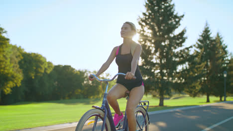 Tired-woman-bicyclist-wiping-sweat-from-face-while-cycling-in-summer-park