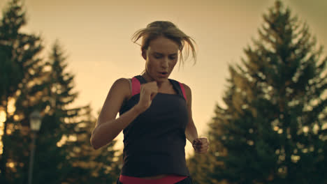 Sport-woman-running-in-park-at-sunset.-Tired-runner-stop-for-break-at-park-road