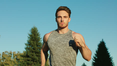 Sport-man-running-in-park-on-blue-sky-background.-Male-runner-run-in-park