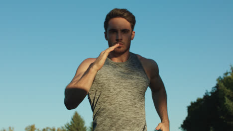 Male-runner-training-cardio-exercise-in-park.-Sport-man-running-on-blue-sky
