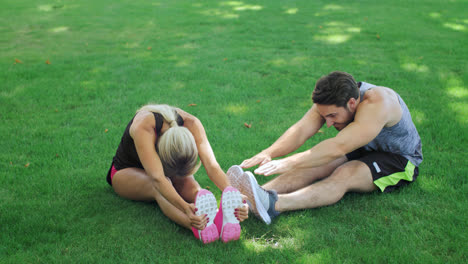 Sport-couple-training-stretch-exercise-on-green-grass-in-summer-park