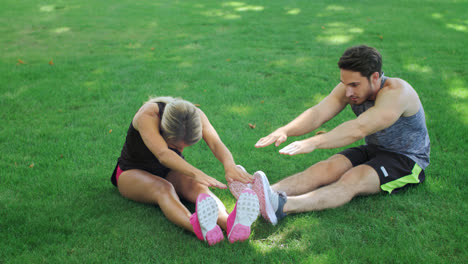 Young-couple-training-stretch-exercises-together-in-summer-park