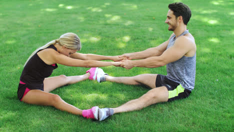 Fitness-trainer-help-woman-stretching-legs-at-warm-up-training-in-park