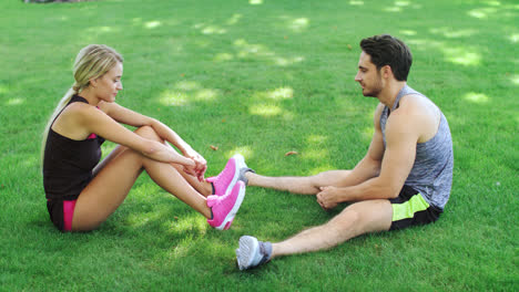 Sport-couple-resting-on-grass-after-outdoor-workout.-Young-man-and-woman