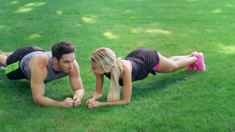 Glücklicher-Mann-Und-Frau-Stehen-Beim-Fitnesstraining-Im-Freien-Auf-Einer-Planke-Auf-Grünem-Gras