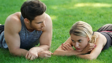 Sport-people-relaxing-after-outdoor-training.-Man-and-woman-lying-on-green-grass