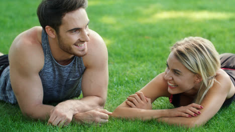 Laughing-man-and-woman-flirting-in-park.-Sport-couple-lying-on-green-grass