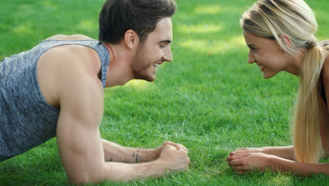Happy-couple-training-plank-exercise-in-summer-park.-Sport-couple-concept