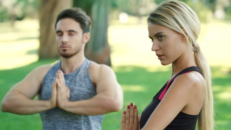 Un-Joven-Y-Una-Mujer-Meditando-En-Una-Pose-De-Yoga-En-Un-Entrenamiento-Al-Aire-Libre-En-El-Parque-De-Verano