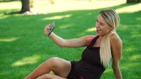 Smiling-woman-taking-selfie-photo-on-mobile-phone-in-park.-Fitness-woman