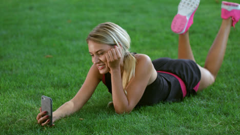 Young-woman-making-video-chat-on-mobile-phone-in-park.-Sport-woman