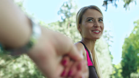 Cheerful-girl-leading-boyfriend-hand-at-fitness-training-in-park.-Follow-me