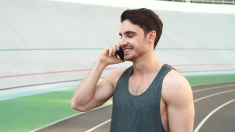 Portrait-of-attractive-runner-male-talking-on-phone-on-track