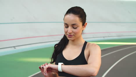 Portrait-of-woman-looking-smart-watch.-Girl-checking-heart-rate-on-sport-field