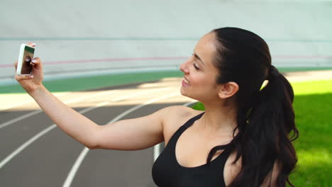 Sport-woman-taking-selfie-photo-on-mobile-phone-at-stadium-track