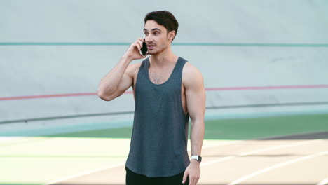 Sport-man-call-mobile-phone-standing-on-track-outdoor.-Fitness-man-talking-phone