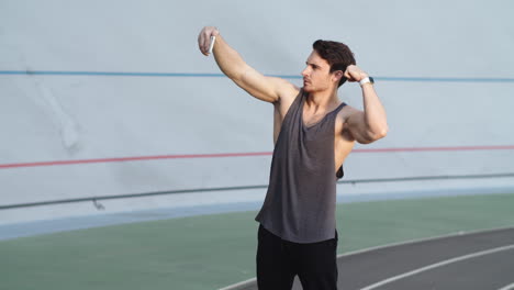 Sport-man-flexing-muscles-for-selfie-photo-on-modern-track