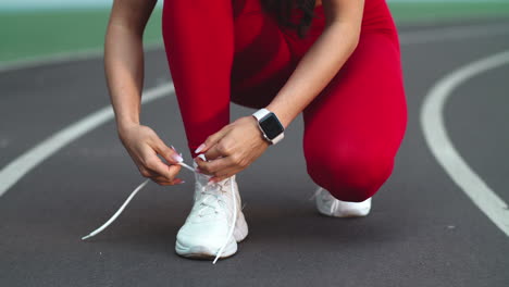 Close-up-of-fitness-woman-lacing-up-footwear-for-marathon-on-track
