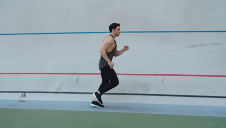 Sport-man-running-in-slow-motion-on-track.-Man-runner-jogging-on-athletics-track