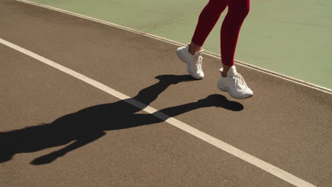 Closeup-female-feet-jogging-in-trainers-on-track.-Girl-running-outdoors-on-track