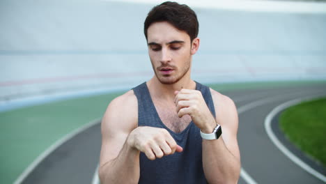 Sporty-man-stretching-arms-before-workout.-Man-exercising-on-athletics-stadium