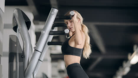 Sport-woman-doing-pulling-up-exercise-on-fitness-machine-in-modern-gym.