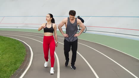 Exhausted-couple-having-break-after-training-together-on-athletics-track