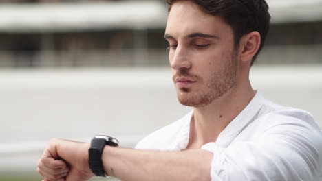 Portrait-of-young-business-man-checking-notifications-on-smart-watch-outdoor