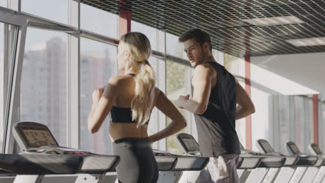 Fitness-couple-running-on-treadmill-machine-in-gym-club-together