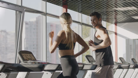 Running-couple-training-cardio-exercise-on-treadmill-machine-in-fitness-center