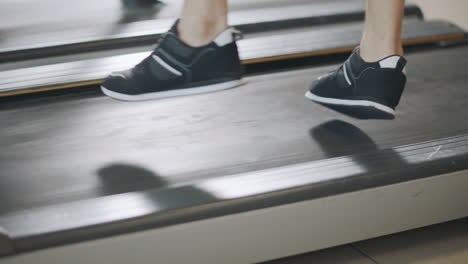 Closeup-feet-running-back-on-treadmill-in-fitness-gym.