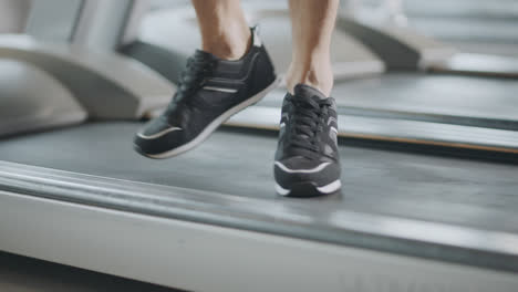 Closeup-feet-moving-on-treadmill-in-fitness-gym.