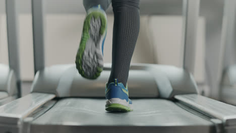 Closeup-athletic-feet-running-on-running-machine-in-fitness-gym.