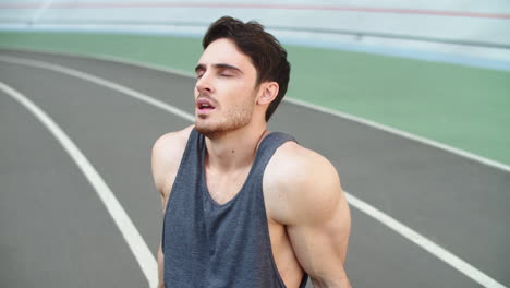 Tired-runner-sitting-on-stadium-track.-Portrait-of-exhausted-man-resting