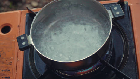 Boiling-water-for-tea-cooking-on-gas-burner-during-hike-tour.-Camping-equipment