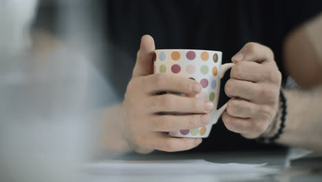 Man-hand-holding-coffee-cup.-Close-up-of-male-hand-preparing-to-drink-tea