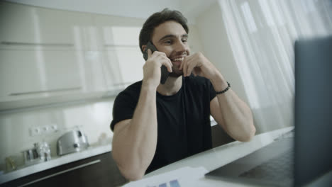 Smiling-man-talking-mobile-phone-at-home-workplace.-Happy-businessman-call-phone