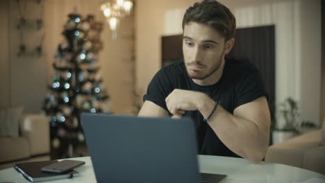 Mann-Benutzt-Laptop-Am-Weihnachtsbaum.-Gelegenheitsgeschäftsmann,-Der-Online-Einkauft