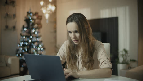 Young-woman-working-on-laptop-computer-at-christmas-home