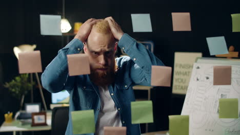 Exhausted-business-man-clutching-head-in-office.-Sad-guy-looking-at-glass-board