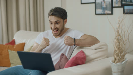Glücklicher-Mann-Feiert-Erfolg-Mit-Laptop-Computer-Auf-Dem-Sofa-Zu-Hause