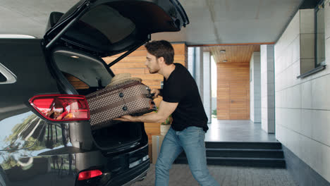 Caucasian-man-loading-suitcase-in-black-car-in-luxury-garage.
