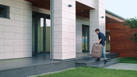 Man-entering-luxury-apartments-with-suitcase.-Casual-man-coming-back-home