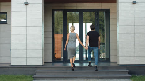 Happy-family-going-inside-luxury-house.-Rich-couple-holding-hands.