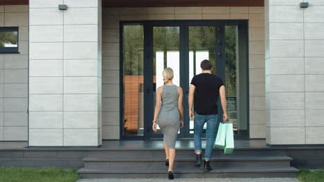 Cute-couple-entering-luxury-house-with-shopping-bags.